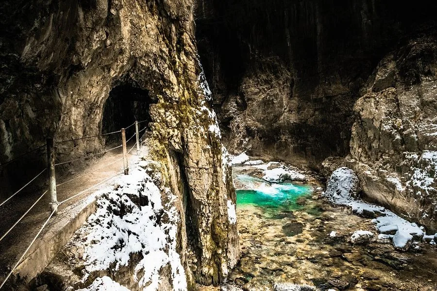 A tunnel mouth opening onto a turquoise pool inside the gorge